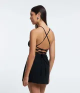 Enterito corto de bengalina color negro, con escote halter, espalda descubierta y tirantes finos cruzados. Presenta corte short pollera.