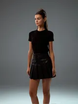 Minifalda negra de cuero sintético con diseño plisado.