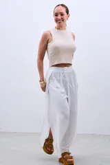 Pantalón blanco de tela fluida con cintura elastizada y cordón ajustable. Presenta aberturas laterales amplias desde la cintura hasta el ruedo.