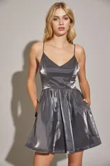 Vestido corto plateado con breteles finos, escote en V y falda acampanada con bolsillos laterales.