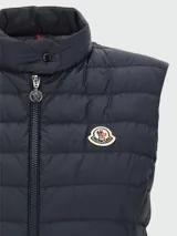 Chaleco puffer azul marino con cierre frontal y cuello alto. Presenta el logo de la marca en el pecho.