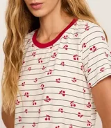 Blusa de pijama de manga corta, corte holgado, con cuello redondo ribeteado en rojo. El tejido es de viscosa con estampado de rayas finas horizontales y pequeños motivos de cerezas en color rojo.