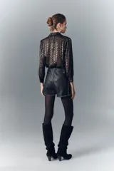 Short de cuero negro con tachas metálicas en ruedo, laterales y presillas.