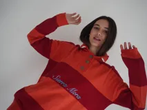 Sweater de hilo de algodón a rayas horizontales rosas y grises, con cuello polo, botones de guampa y bordado de Sierra Mora a tono.
