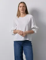 Blusa de gasa blanca, marca Sioni, con mangas 3/4 y aplique de volados.