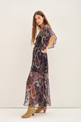 Vestido largo con estampado paisley en tonos azul, negro, rojo y dorado. Tiene escote en V, mangas cortas amplias, elástico en la cintura con lazo y está confeccionado en viscosa con jacquard de lurex.