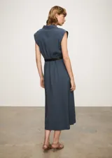 Vestido camisero midi color beige, sin mangas, con cuello camisero, cinturón ajustable y aberturas laterales.