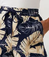Short runner de viscosa con estampado de hojas en tonos beige y negro. Tiene cintura elástica con cordón ajustable, dos bolsillos laterales y dobladillo redondeado.
