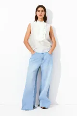 Blusa blanca sin mangas con cuello mao y pechera de volados con bordados de encaje.