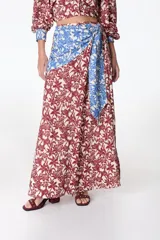 Falda larga con estampado floral en tonos rojo y beige, con detalle de nudo en la cintura en tela celeste con estampado floral.