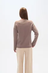 Sweater color lila con apliques de lentejuelas doradas formando un diseño floral en el frente.