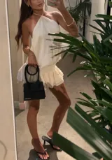 Vestido corto color crema, con escote halter, espalda descubierta y falda con volados.