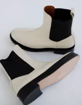Bota Chelsea color crema de cuero vacuno, con elástico lateral negro, suela de cuero y taco de 2,5 cm. Hecha a mano en Argentina.