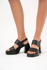 Sandalias negras de cuero sintético con plataforma delantera y tacón ancho forrado con textura croco. Tienen doble tira ancha sobre el empeine, ajuste con hebilla y suela de goma.