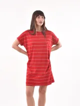 Vestido corto de algodón color rojo con rayas horizontales blancas. Tiene cuello redondo, manga corta doblada y un bolsillo de parche en el pecho.
