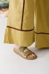 Sandalias bajas color verde oliva con dos tiras con borde festoneado y tachas doradas.