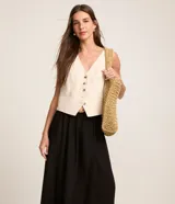 Pollera midi evasé color negro, confeccionada en viscolino, con trabillas en la cintura y cinturón de ráfia con hebilla redonda.