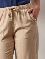 Pantalón color beige, marca Dash, de corte cropped y pretina trasera elastizada. Presenta bolsillos delanteros y traseros.