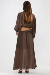 Blusa corta color marrón chocolate en tejido arrugado liviano, con cuello mao, botones al frente y mangas abullonadas terminadas con ruedo elastizado.