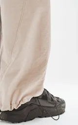 Pantalón beige de corte sastrero con bolsillos laterales, estilo holgado y tela suede. Cintura trasera con doble ajuste elástico y tanca, cintura delantera con botón y cierre.