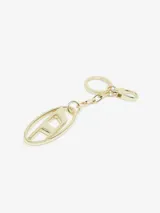 Llavero de metal color dorado con un dije principal en forma de placa ovalada que contiene la letra 'D' estilizada. Se sujeta mediante una cadena corta a un mosquetón.