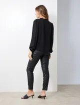 Blusa de gasa laminada de color negro, con escote en V, botones y hombros con detalle en punto smock.