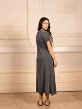 Vestido largo gris con estampado de concha y texto en rosa y amarillo. Tiene escote en V, mangas cortas y tajo lateral.