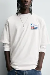 Camiseta blanca de corte relaxed fit, cuello redondo y manga corta. Estampado frontal con diseño gráfico en azul y rojo con texto en chino y la leyenda "Eastern Division 90".