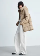 Campera puffer color beige con capucha, cierre frontal con cremallera y bolsillos laterales.