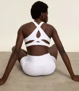 Top deportivo blanco con escote halter y tiras diferenciadas en la espalda. Confeccionado en microfibra acanalada y levemente brillante.