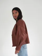 Campera oversize de cuero color marrón con cierre frontal y detalles de costuras en los bordes.
