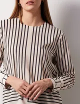 Blusa de gasa estampada a rayas verticales blancas y negras, marca Sioni. Espalda con abertura y botón. Manga larga con puño y botón.