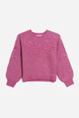 Sweater tejido de punto color fucsia con cuello redondo y mangas largas abullonadas. Presenta apliques de flores en relieve en el frente y en las mangas.