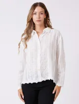 Camisa de algodón blanca con bordados florales verticales, cuello con solapa y cierre frontal con botones.
