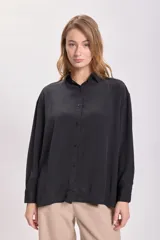 Camisa negra de manga larga con cuello clásico y cierre frontal con botones.
