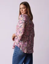 Blusa estampada con flores en tonos rosa, naranja y azul marino. Tiene escote en V con detalle de pliegues y mangas 3/4 con volados.