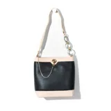 Cartera tipo tote bag de símil cuero color negro con detalles en beige. Tiene correa de hombro, cierre con broche metálico y cadena decorativa.
