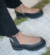 Bota de cuero vacuno con suela de goma, diseño de punta cuadrada, elástico exterior y cierre interno.
