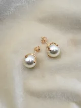 Aros colgantes con perlas blancas engarzadas en metal dorado.