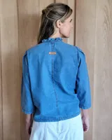 Camisa negra con mangas fruncidas, botones de nácar y pespuntes contrastantes.