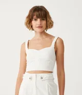 Blusa cropped blanca de lino con escote en V y tirantes trenzados.