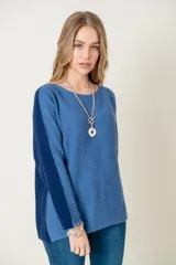 Sweater de lana gris claro con mangas largas y corte holgado. Presenta una franja vertical gris oscuro a lo largo de cada manga.