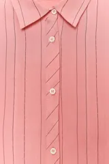 Camisa oversize color salmón con rayas verticales finas en color negro. Cuello solapa, manga larga con puños y cierre frontal con botones.