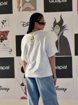 Remera blanca de corte oversize con estampado frontal de Mickey Mouse en movimiento y texto "Mickey Mouse" en rosa.