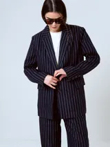 Blazer azul marino con rayas verticales blancas, de corte clásico, con solapas de muesca, cierre frontal con dos botones, bolsillos con solapa y abertura en la espalda.