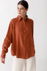 Camisa blanca de lino con botones de madera, corte recto y mangas largas.