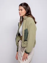Campera cropped verde militar de polar con capucha y cuello alto, cierre frontal a tono, puños y cintura elastizados. Tiene dos bolsillos frontales de nylon con solapa.