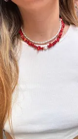 Collar de cuentas rojas y perlas, con cadena ajustable en la parte posterior.