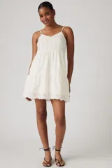 Vestido corto blanco con bordado inglés, breteles finos y falda escalonada.