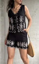 Conjunto negro de lino con bordados florales blancos. Incluye chaleco con lazo frontal y short con ruedo festoneado.